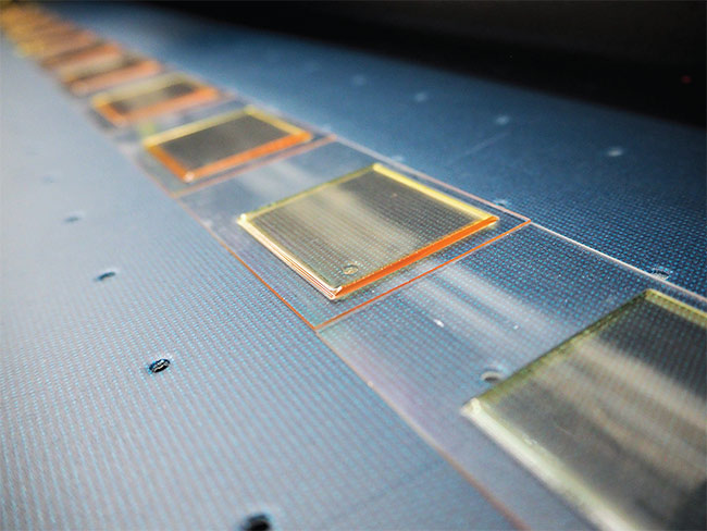 A dozen planar Alvarez lenses are produced on a NanoVox pilot line with 1-µm drop precision. The line can print lenses measuring in size from 500 µm to 5 in. Scaling volume will require advancements in inkjet equipment, printing materials, and processes. Courtesy of NanoVox.