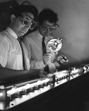 A laser in operation at the Electronics Resource Centers Space Optics Laboratory is checked by Lowell Rosen (left) and Dr. Norman Knable.