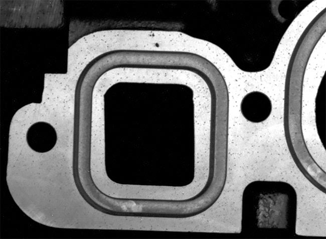 An engine block (top must be inspected for pores (bottom) and other defects. Flexible camera positioning solves this challenging vision task. Courtesy of LEONI Engineering Products and Services.