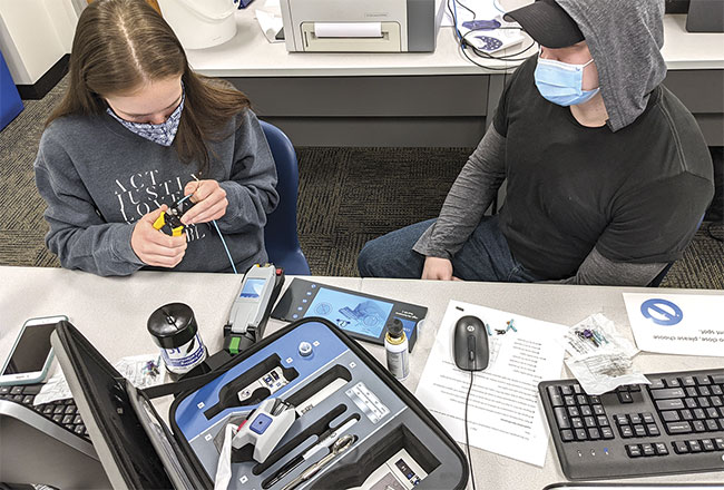 Iowa Western Community College students apply a connector to a fiber optic cable. Courtesy of IWCC.