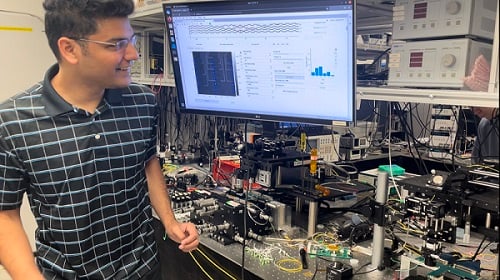 Researchers have developed a new light-based computing scheme called LightHash that reduces the energy necessary for cryptocurrency and blockchain applications. First author Sunil Pai is pictured with the optical setup used for the new research. Courtesy of LightHash.