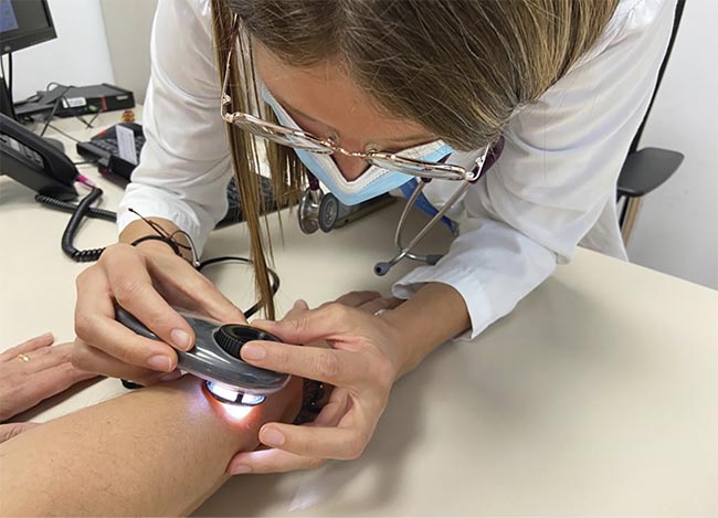 Figure 1. Anna Escalé-Besa, a clinician at Institut Catala de la Salut, examines a patient’s skin with a dermatoscope. Courtesy of Institut Catala de la Salut.