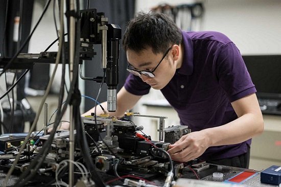 Researcher Zhengdong Gao adjusts a new “all in one” microcomb laser device created in the lab of professor Qiang Lin. Courtesy of the University of Rochester/J. Adam Fenster.