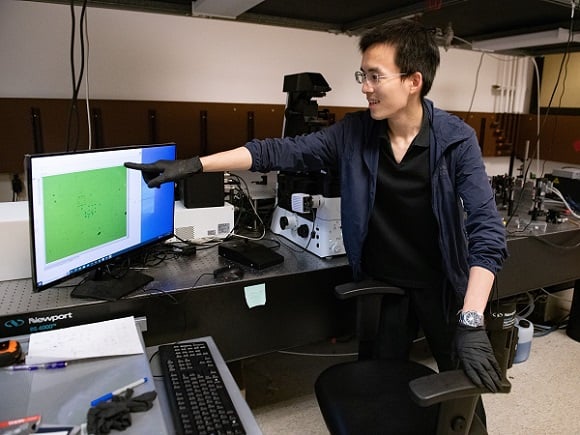 Siyuan Huang, a graduate student in Yuebing Zheng’s lab, demonstrates the technology that uses plastics and other materials with a laser to break them down into their smallest parts for future reuse. Courtesy of the University of Texas at Austin.