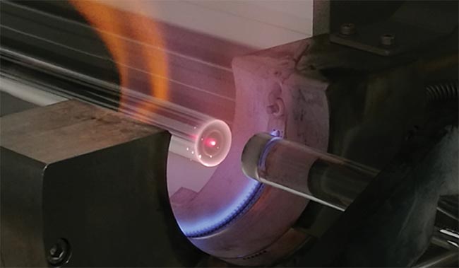 Preform fabrication is performed to achieve a modified core to cladding ratio in the finished fiber (top).  Hydroxyl group absorption and laser emission opportunities band in silica fibers (bottom). EDFA: erbium-doped fiber amplifier; HDFL: holmium-doped fiber laser; TDFL: thulium-doped fiber laser; YDFL: ytterbium-doped fiber laser. Courtesy of Coractive Inc.