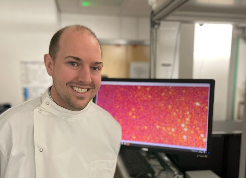 Steven Quinn in front of a screen showing amyloid proteins being detected on glass using a microscope. Courtesy of the University of York.