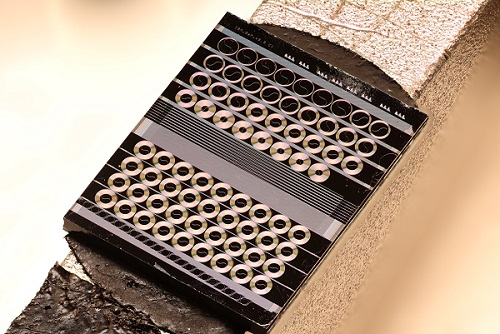 A focus-stacked macro photograph of a fabricated gallium phosphide photonic chip featuring multiple spiral waveguides and other test structures. The chip width is just 0.55 cm across. Due to the high Kerr nonlinearity of gallium phosphide, its high refractive index, and its negligible two-photon absorption, extremely efficient optical parametric amplification and frequency conversion over S, C, and L optical communication bands are achieved using this chip. Courtesy of EPFL/Nikolai Kuznetsov.