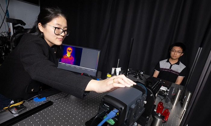 Researcher Dingding Han adjusts a thermal camera capturing an image of researcher Corey Zheng. Using an advanced processing technique on the raw thermal image, the researchers can accurately measure body temperature, heart rate, and respiration rate. The noncontact technology could open new possibilities for vital sign monitoring and early disease detection. Courtesy of Georgia Institute of Technology/Candler Hobbs.